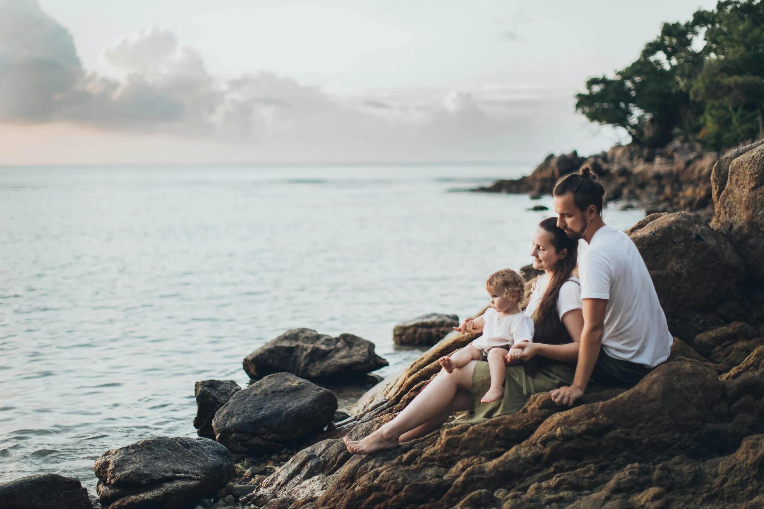 Family sitting on rocks by the sea