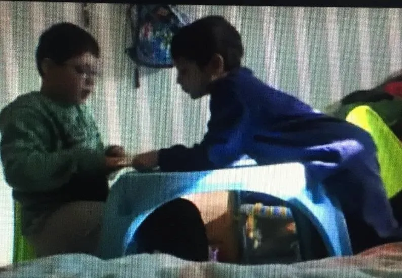 Siblings face-to-face book reading position